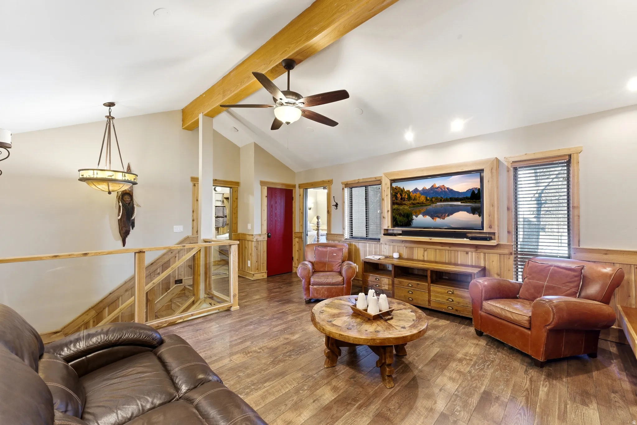 Living area featuring wainscoting, hardwood / wood-style flooring, ceiling fan, beam ceiling, and wooden walls