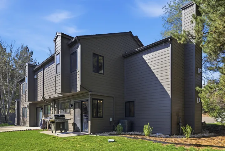 Back of house with a chimney, a lawn, and a patio area