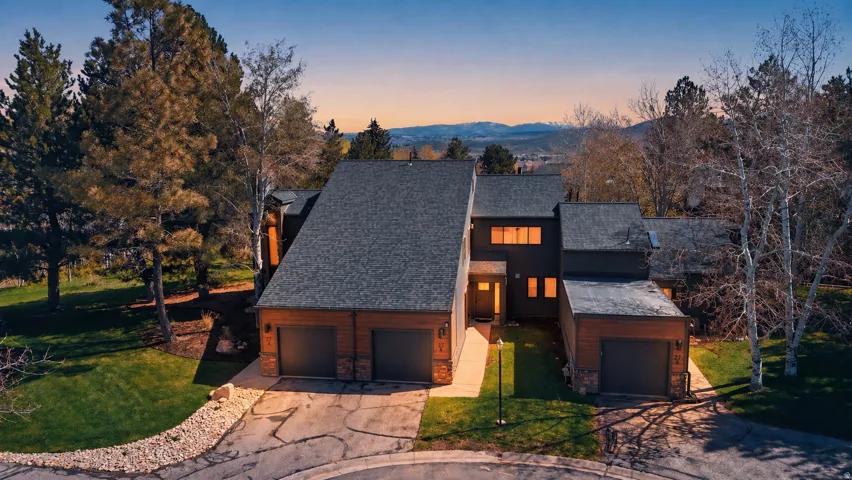 View of front of property featuring a front lawn, stone siding, a mountain view, and concrete driveway