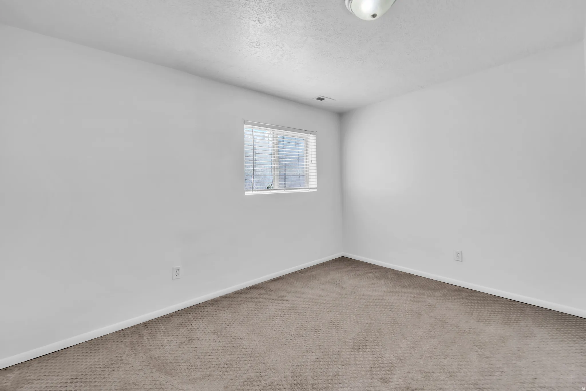 Spare room featuring carpet flooring and a textured ceiling