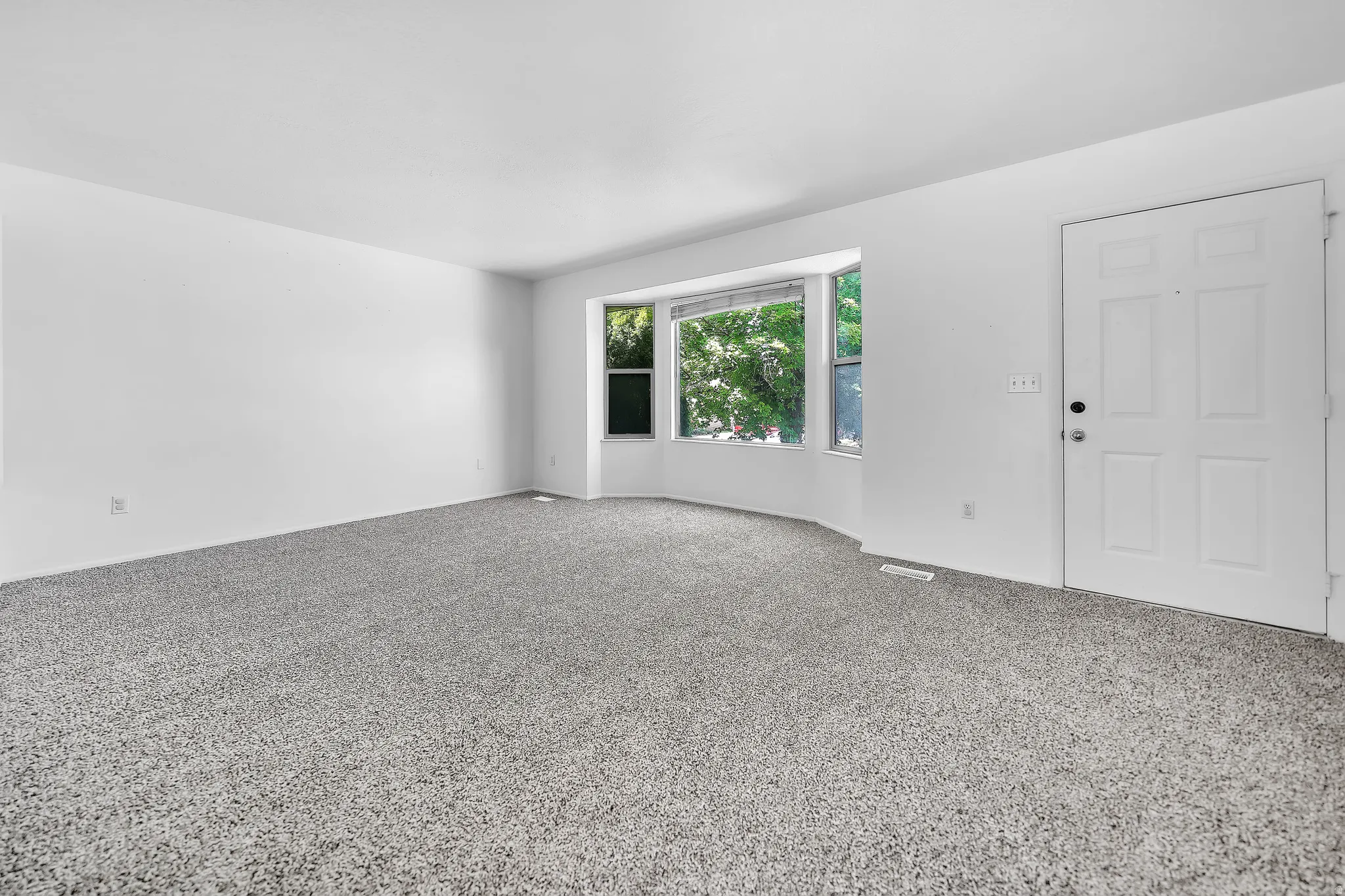 Spacious room featuring light gray carpet flooring and white painted walls