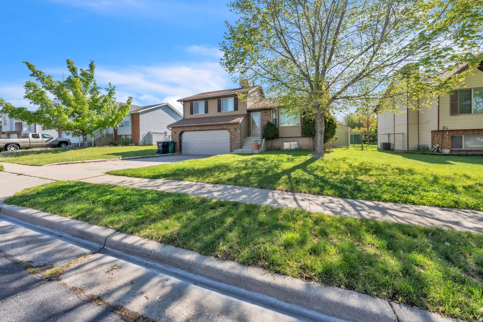 Split level home with brick siding, concrete driveway, a garage, and a residential view