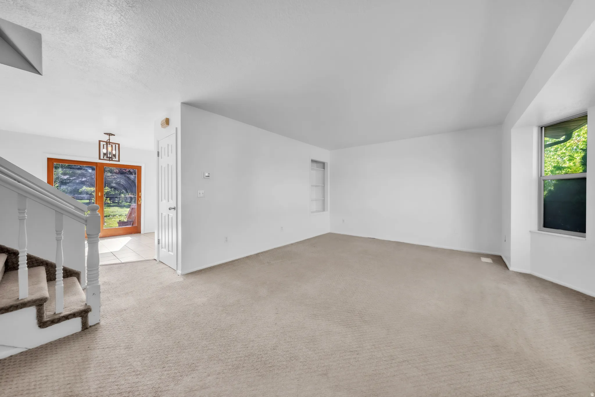 Unfurnished living room with light colored carpet and a textured ceiling