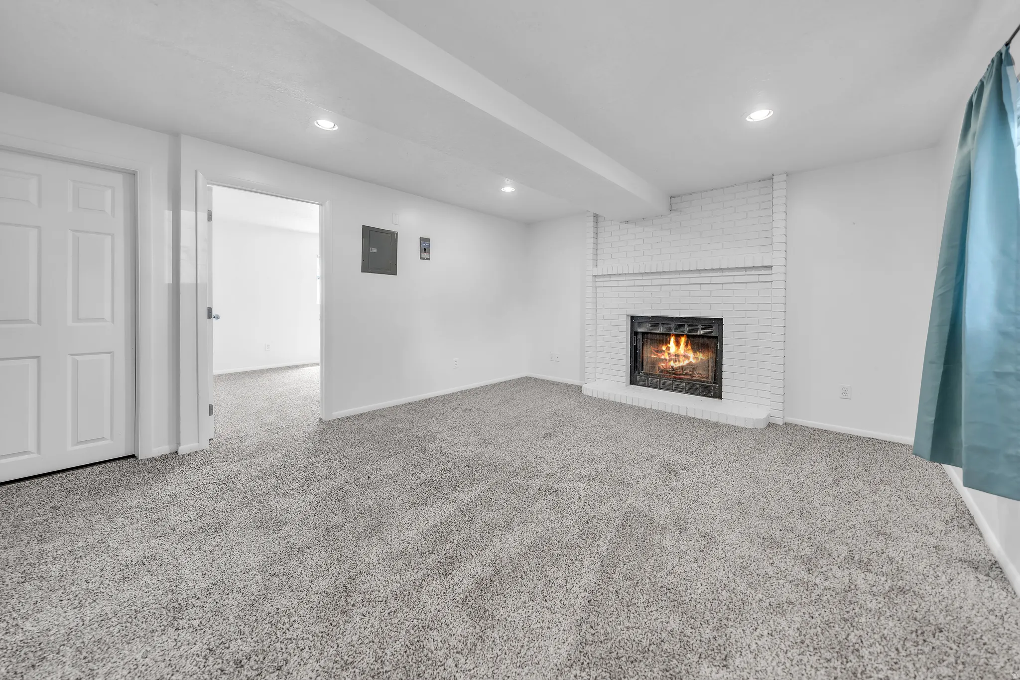 Living area featuring a white brick fireplace, recessed lighting, and soft gray carpeting