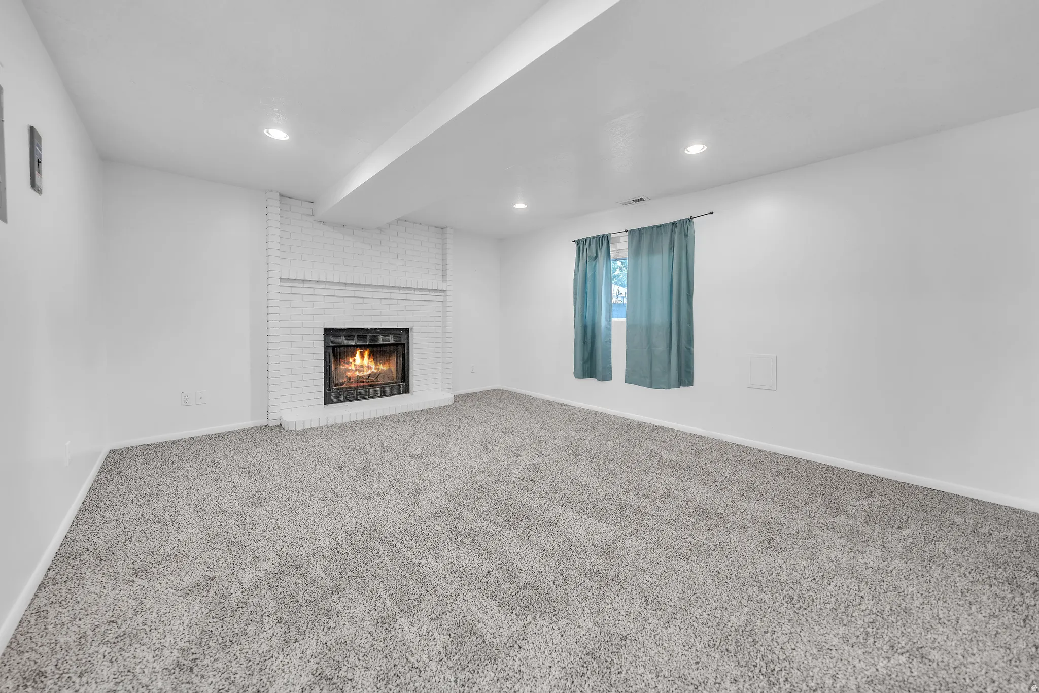 Spacious room featuring a white brick fireplace, recessed lighting, and soft gray carpeting