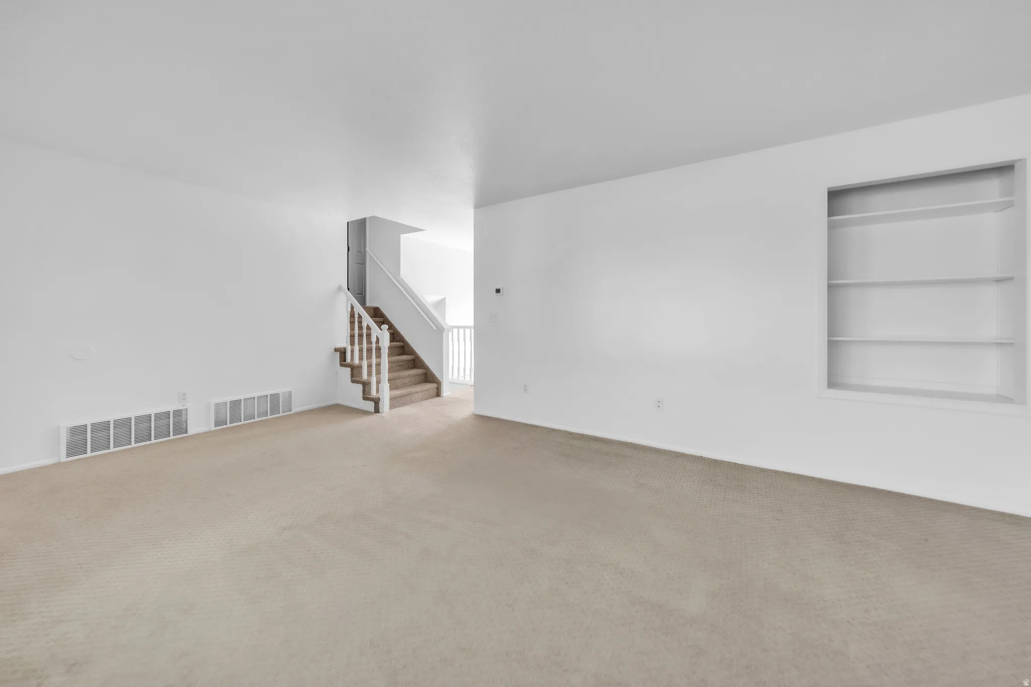 Carpeted spare room with stairway and built in shelves