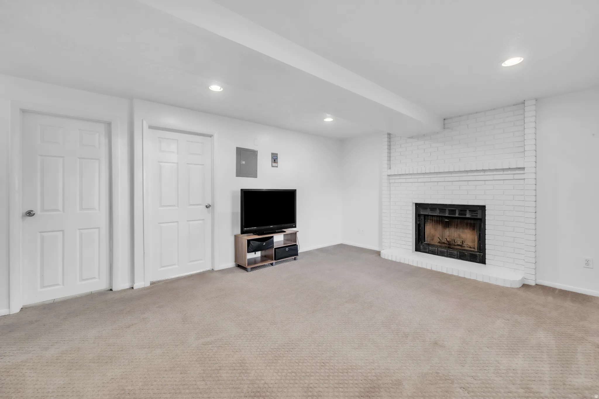 Unfurnished living room with carpet, recessed lighting, electric panel, and a brick fireplace