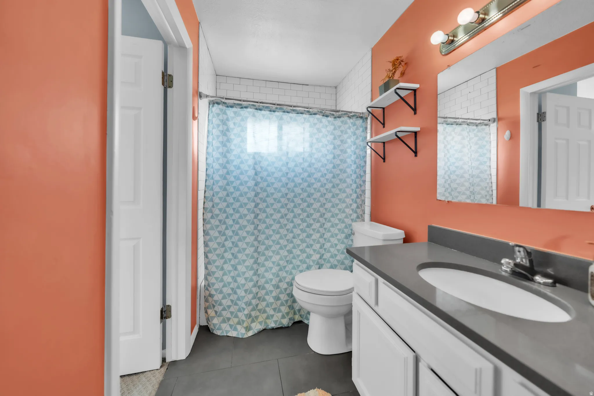 Full bath with vanity, curtained shower, and dark tile patterned flooring
