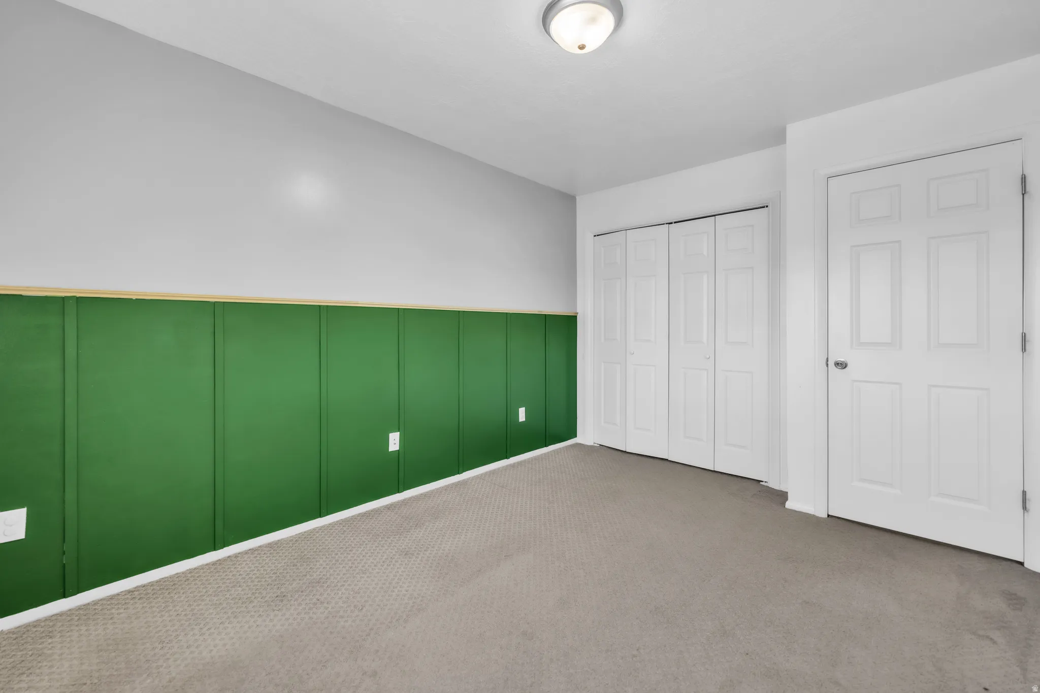 Unfurnished bedroom featuring a decorative wall, a closet, and carpet floors