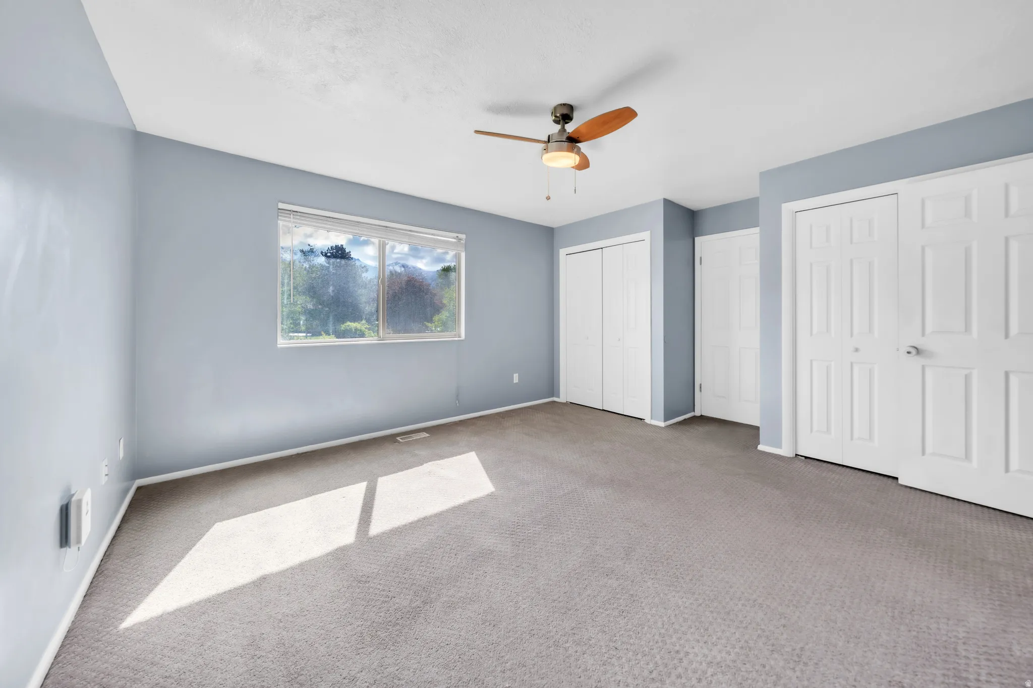 Unfurnished bedroom featuring multiple closets, carpet floors, and a ceiling fan