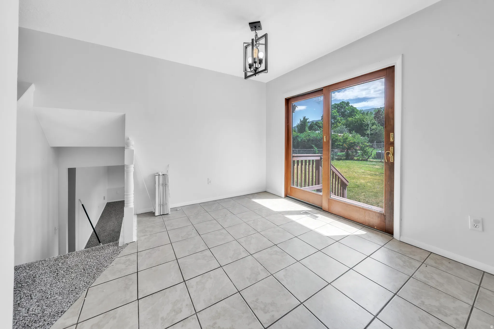Sliding wood-frame glass doors opening to an exterior wood deck and green space