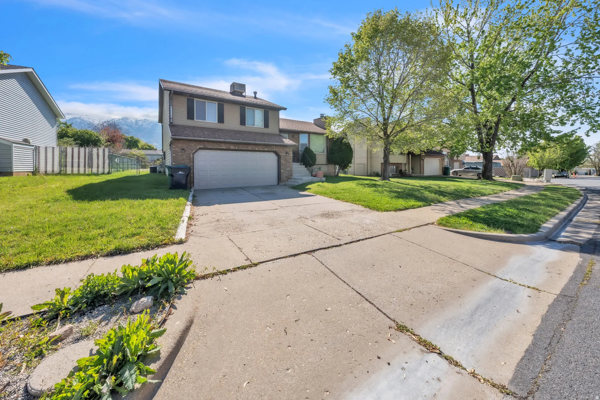 Split level home featuring a front yard, driveway, an attached garage, and brick siding