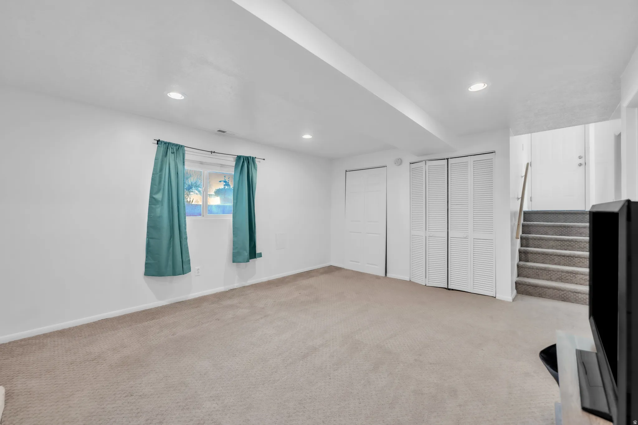 Unfurnished bedroom featuring light colored carpet, multiple closets, and recessed lighting