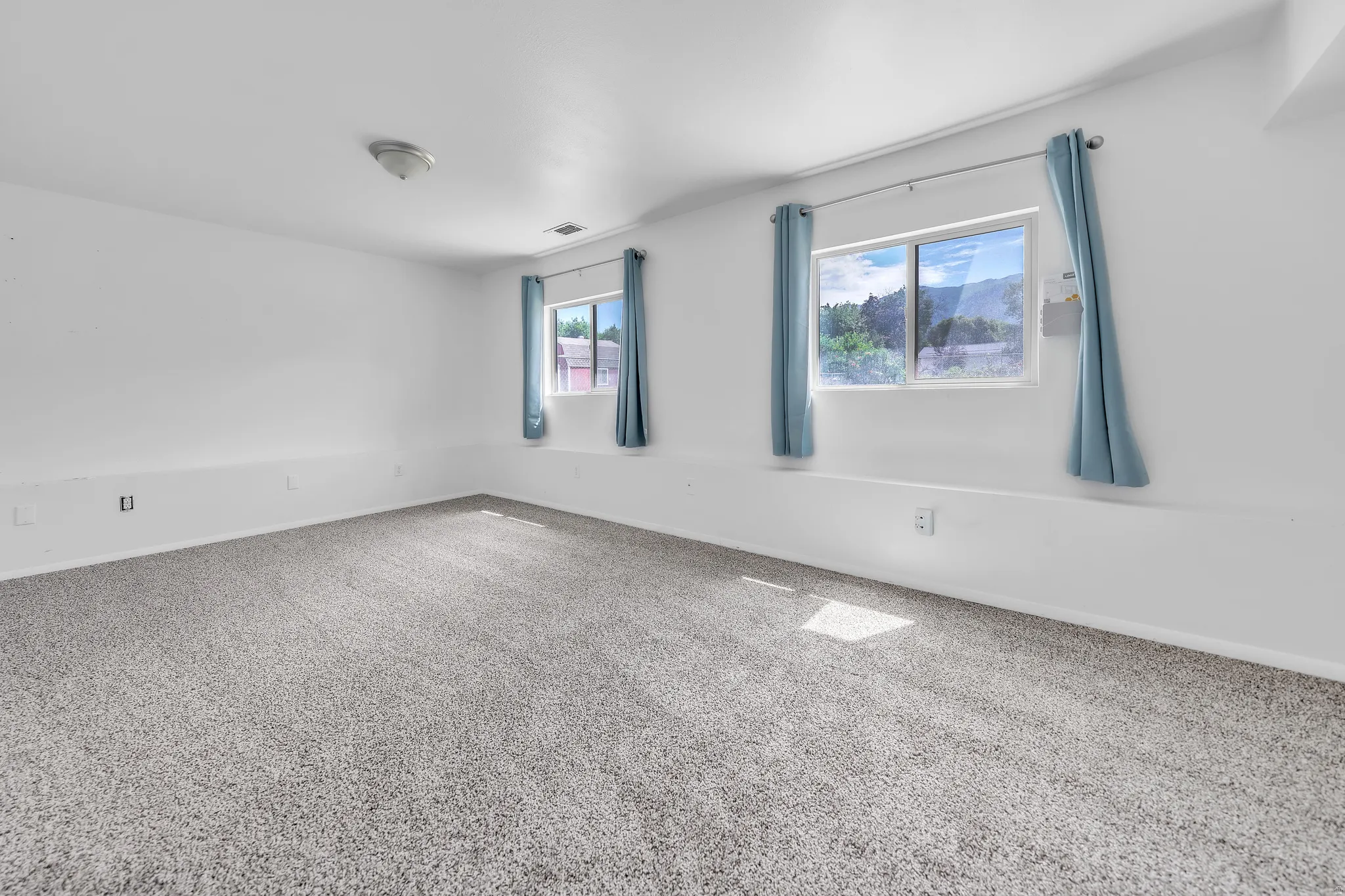 Bright room with two windows and light-colored carpeting