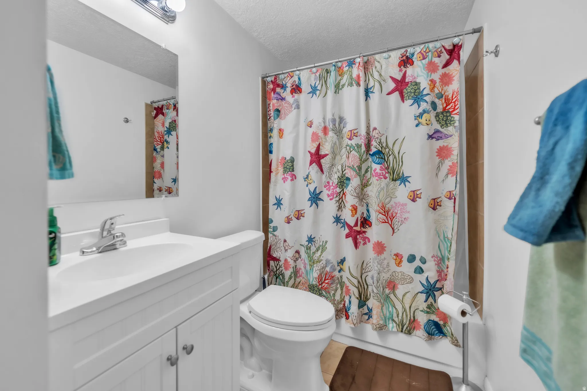 Bathroom with vanity, a textured ceiling, and shower / bathtub combination with curtain