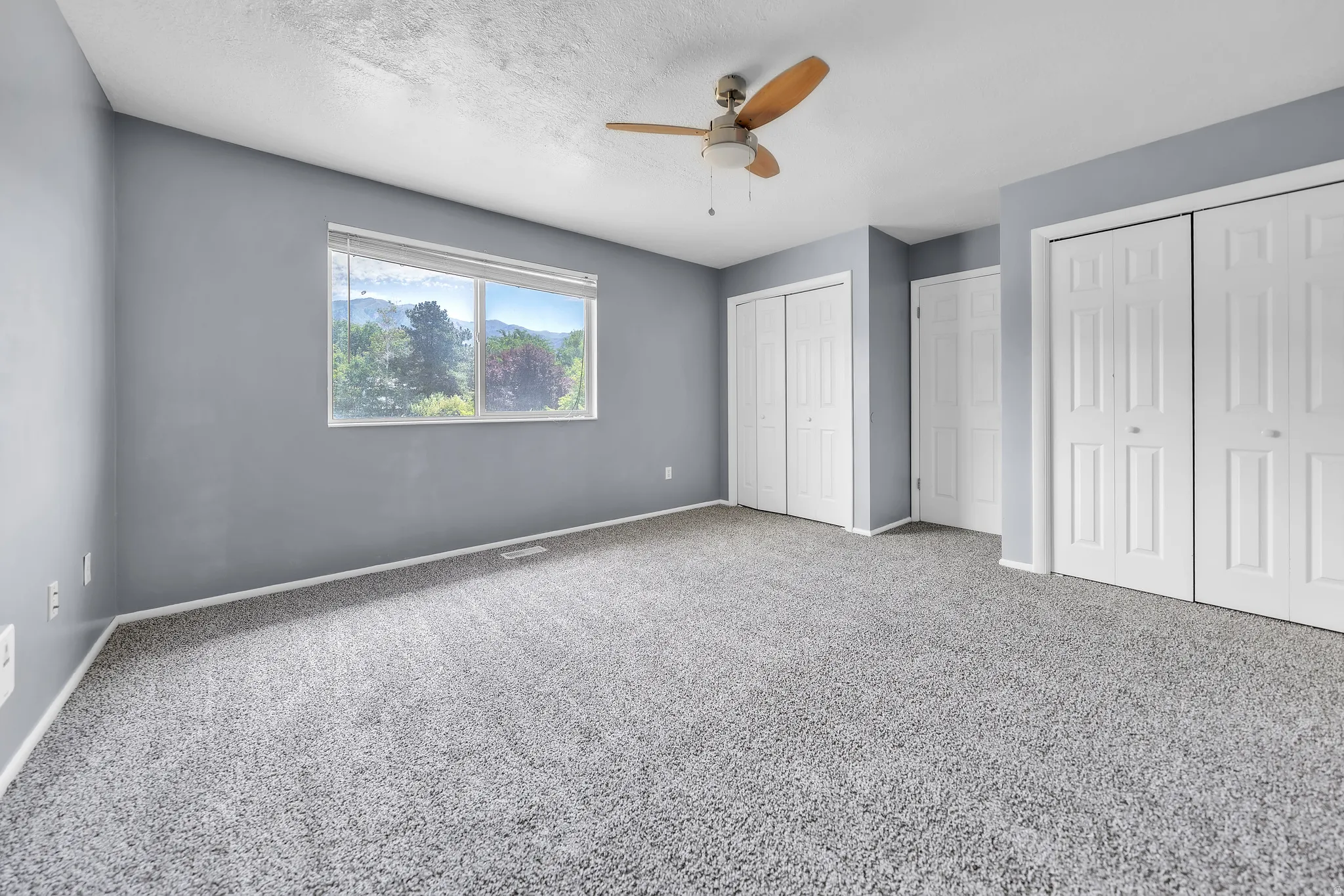 Spacious room with gray textured carpet and matching wall paint