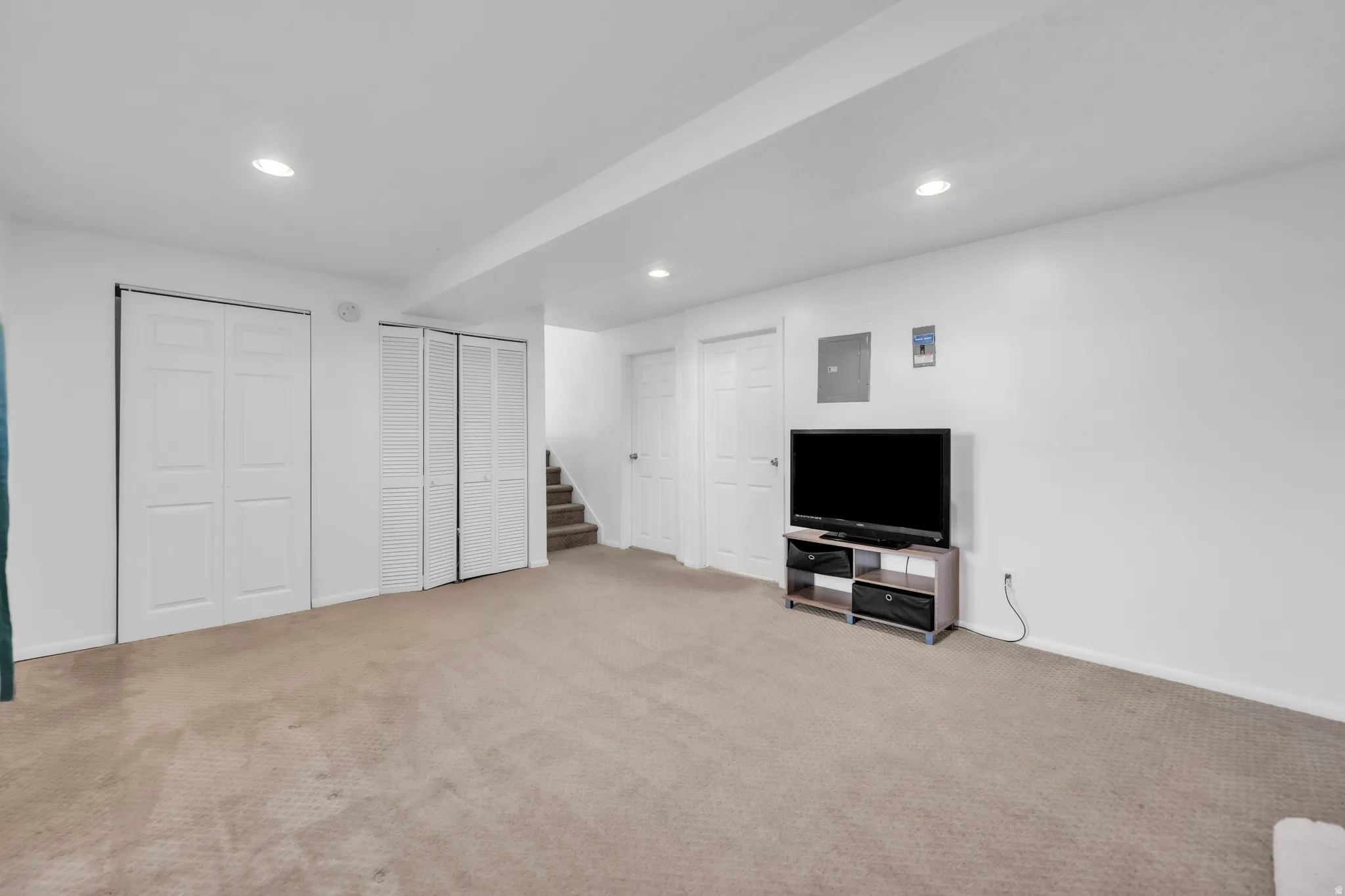 Finished below grade area featuring recessed lighting, light carpet, and electric panel
