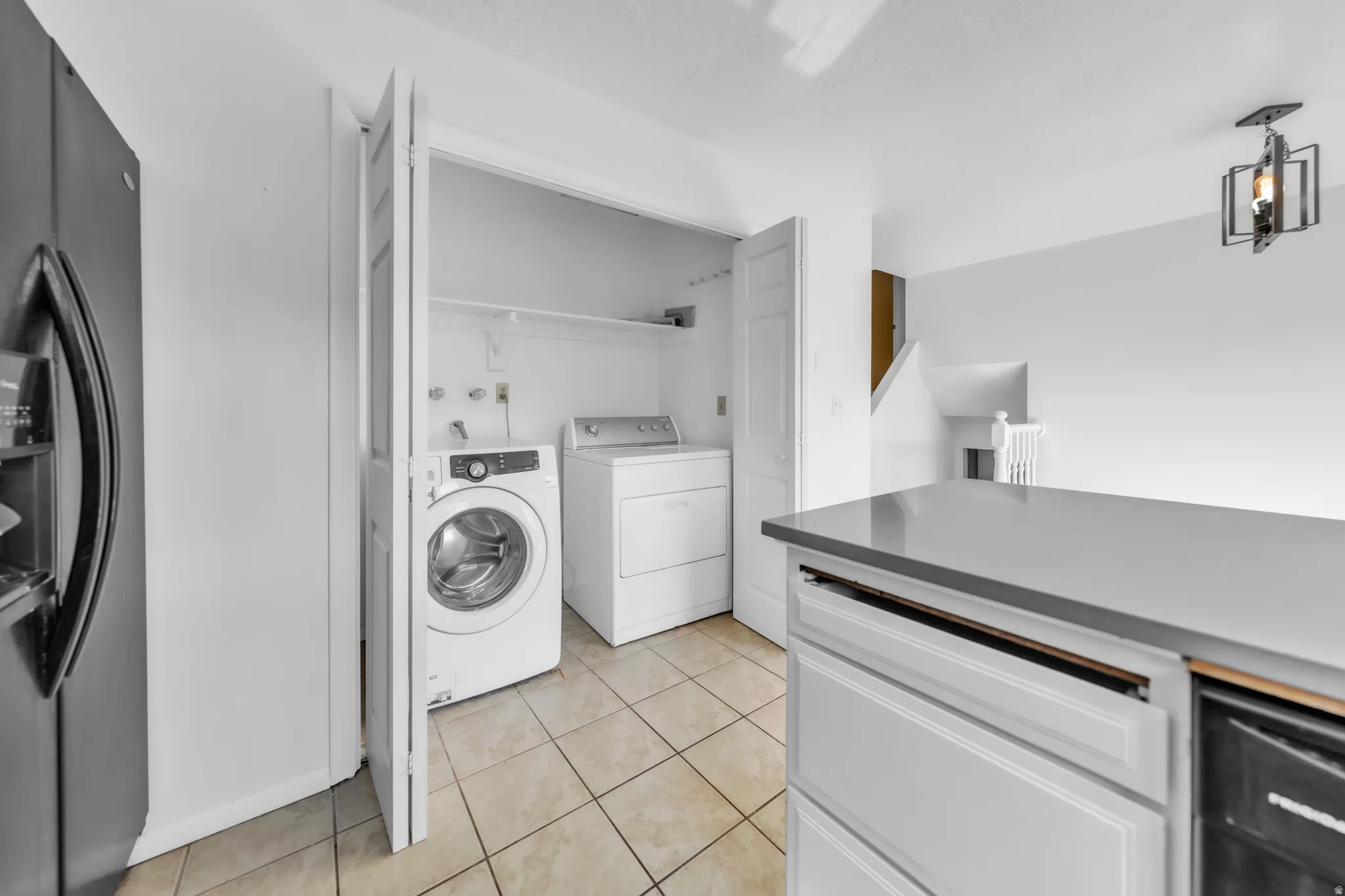 Laundry area with washing machine and clothes dryer and light tile patterned flooring