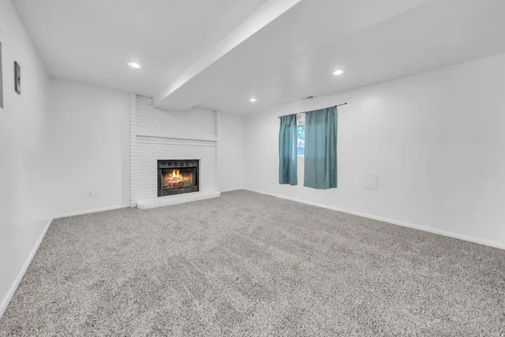 Spacious room featuring a white brick fireplace, recessed lighting, and soft gray carpeting