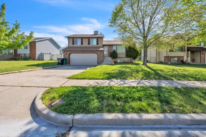 Split level home with a chimney, driveway, brick siding, and an attached garage