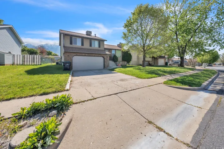 Split level home featuring a front yard, driveway, an attached garage, and brick siding