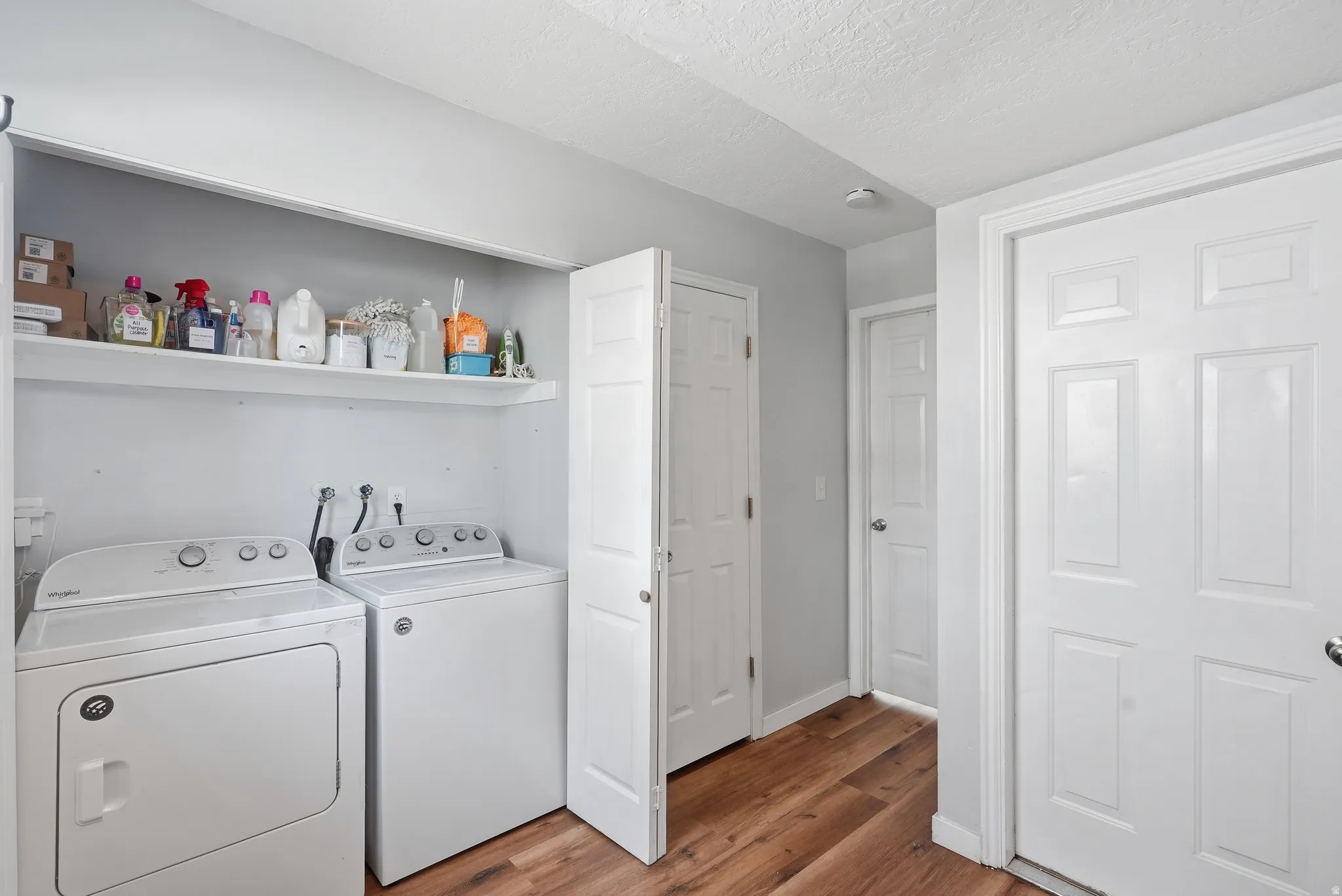 Laundry area with light wood finished floors, separate washer and dryer, and a textured ceiling