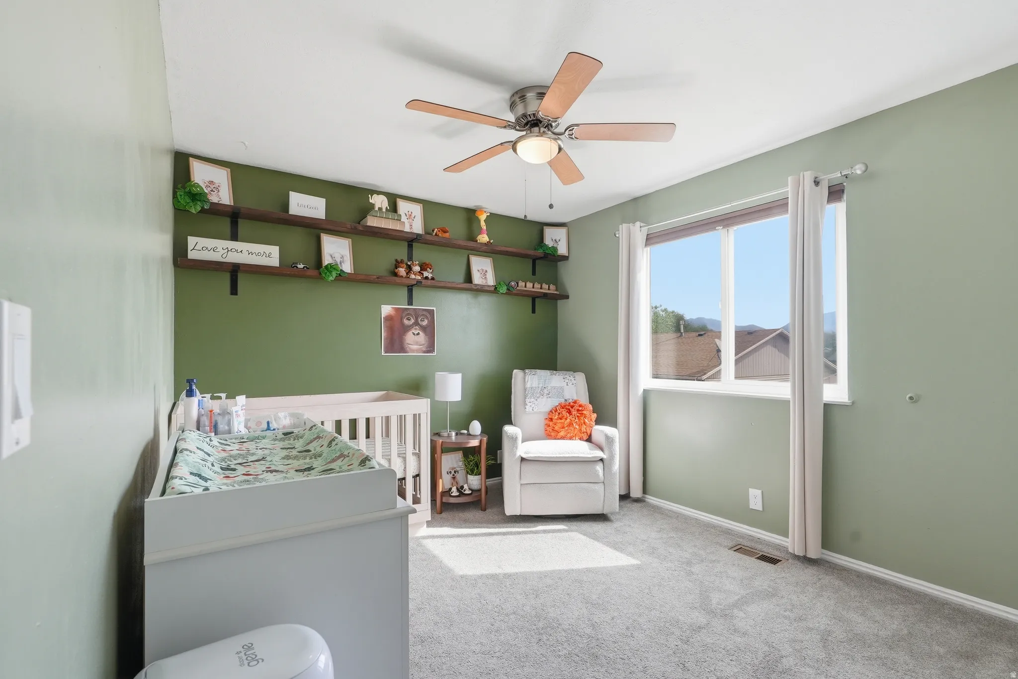 Bedroom featuring a nursery area, light carpet, and ceiling fan