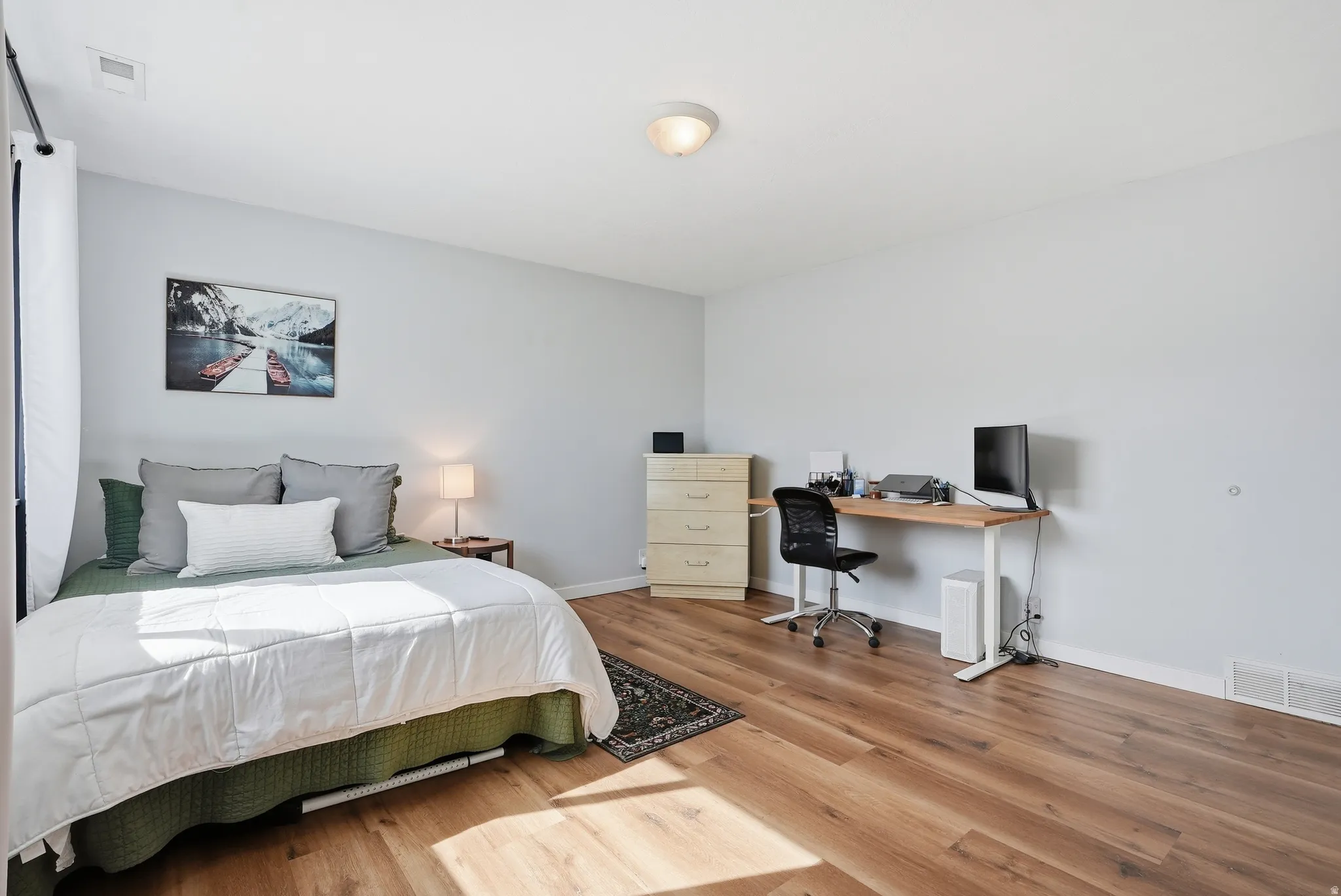 Bedroom with light wood-style floors and an office area