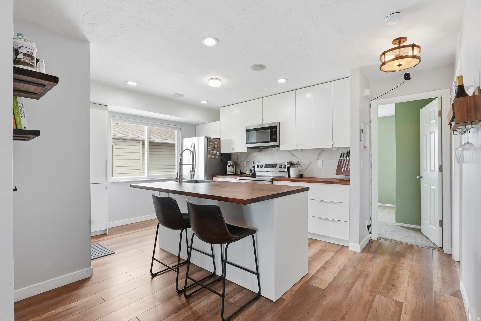Kitchen featuring wood counters, white cabinetry, light wood-style flooring, stainless steel appliances, and recessed lighting
