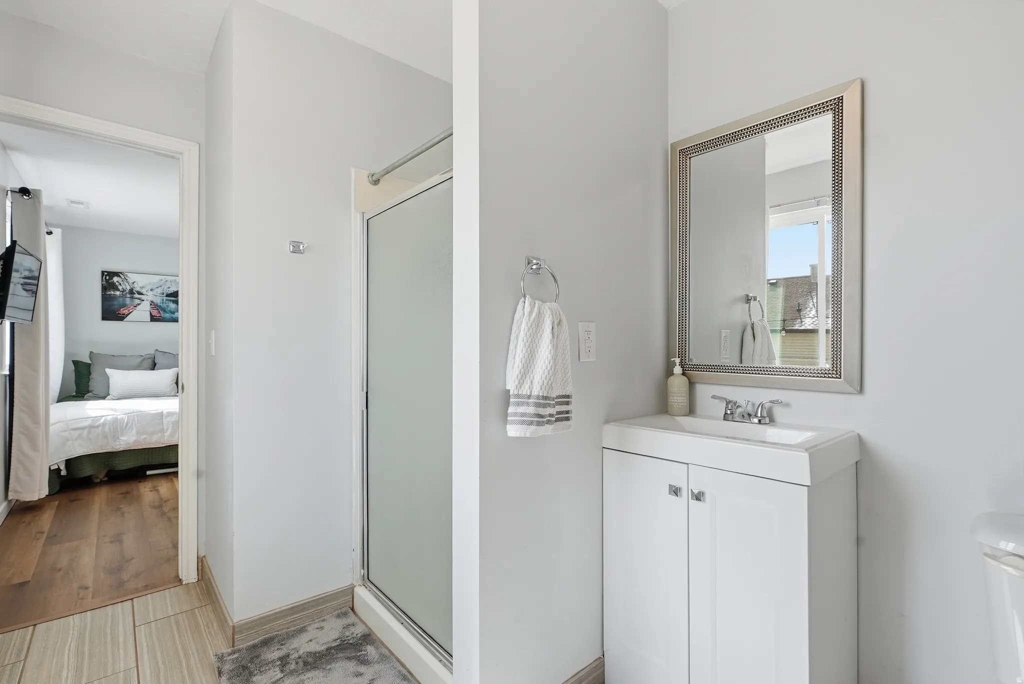 Bathroom with vanity, a stall shower, ensuite bath, and light wood-style floors
