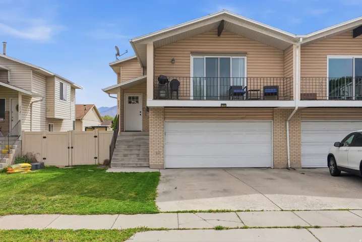 View of front of home featuring a gate, brick siding, concrete driveway, a garage, and a balcony