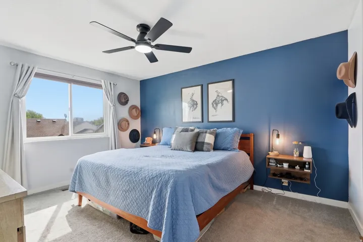 Carpeted bedroom with a ceiling fan and an accent wall