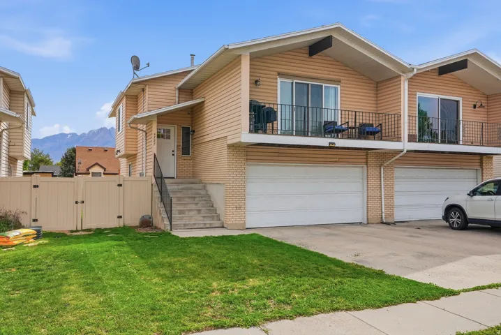 View of front facade featuring a gate, a garage, concrete driveway, brick siding, and a balcony