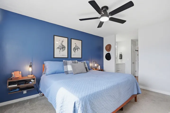 Carpeted bedroom with ensuite bath and ceiling fan