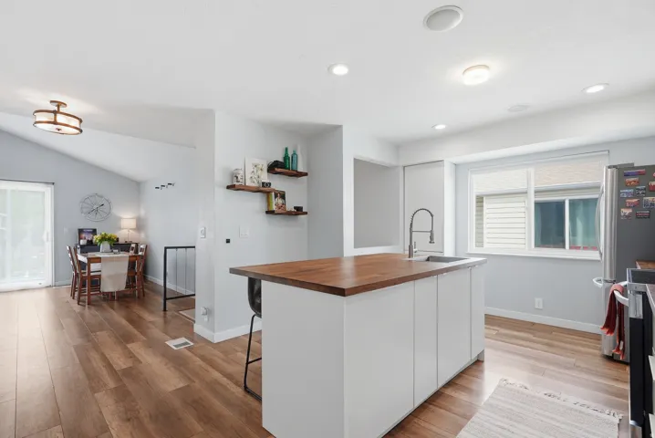 Kitchen featuring wooden counters, healthy amount of natural light, a kitchen breakfast bar, light wood finished floors, and lofted ceiling