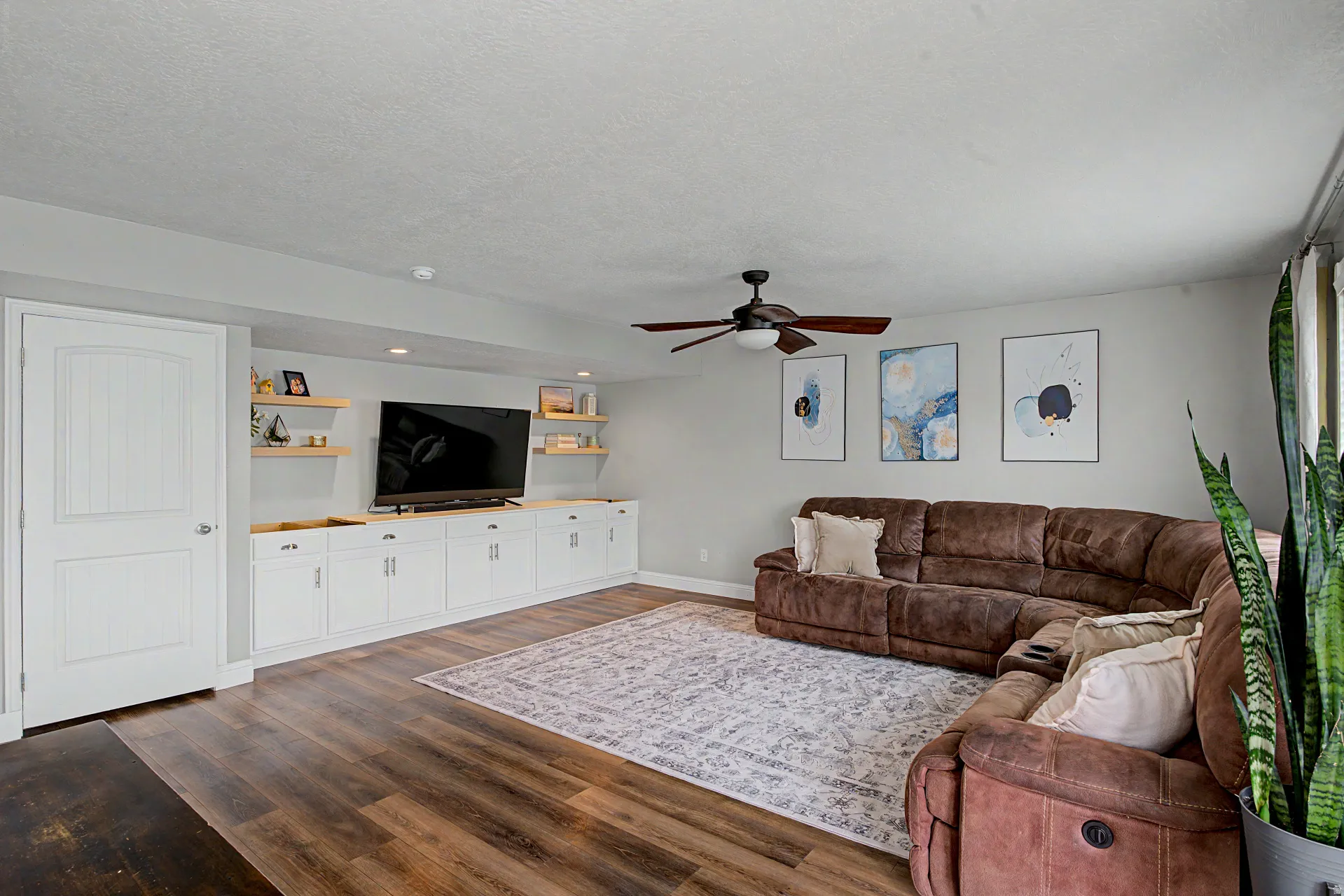 Living room with ceiling fan, dark wood-style flooring, and a textured ceiling