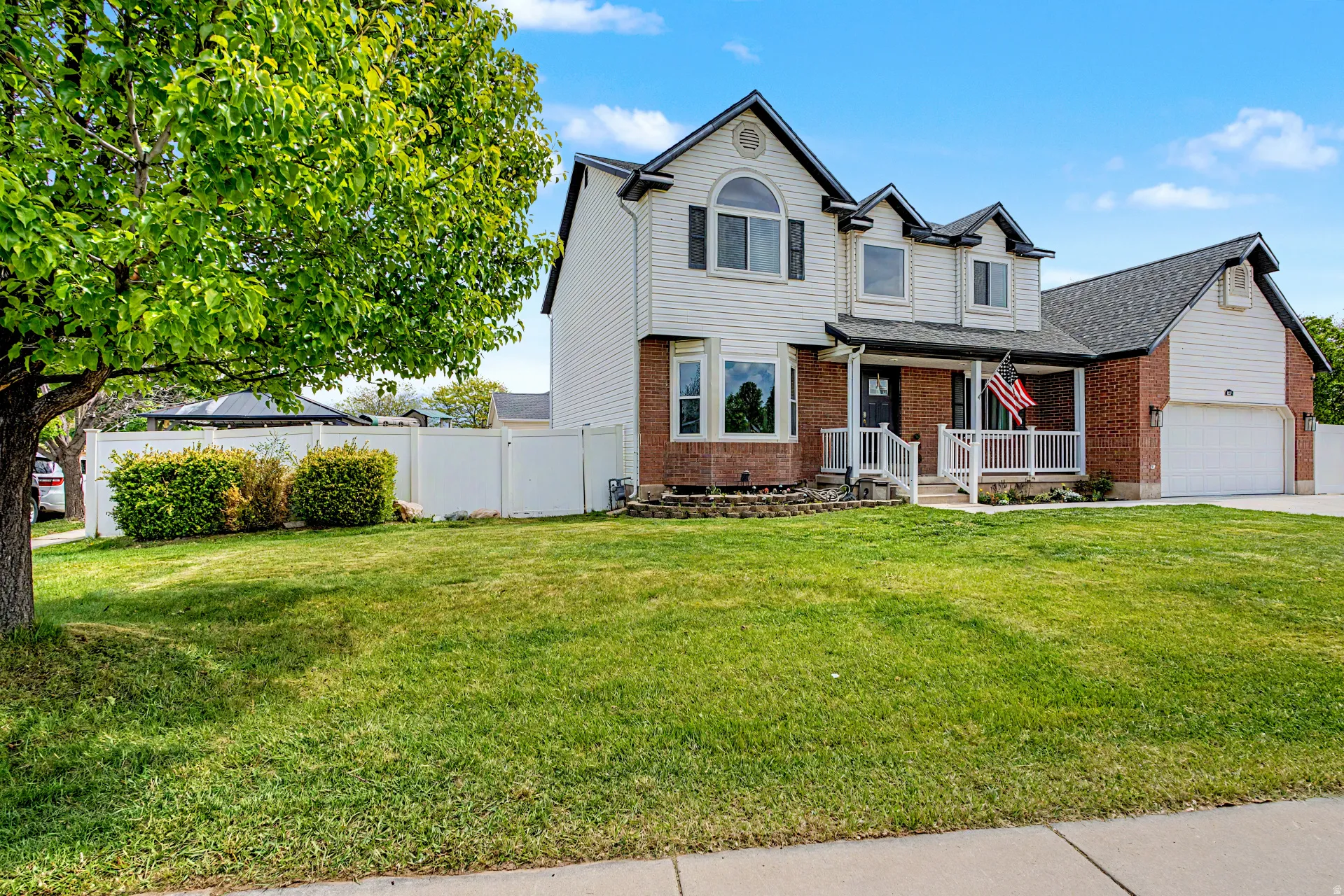 Traditional home with brick siding, a porch, driveway, and an attached garage