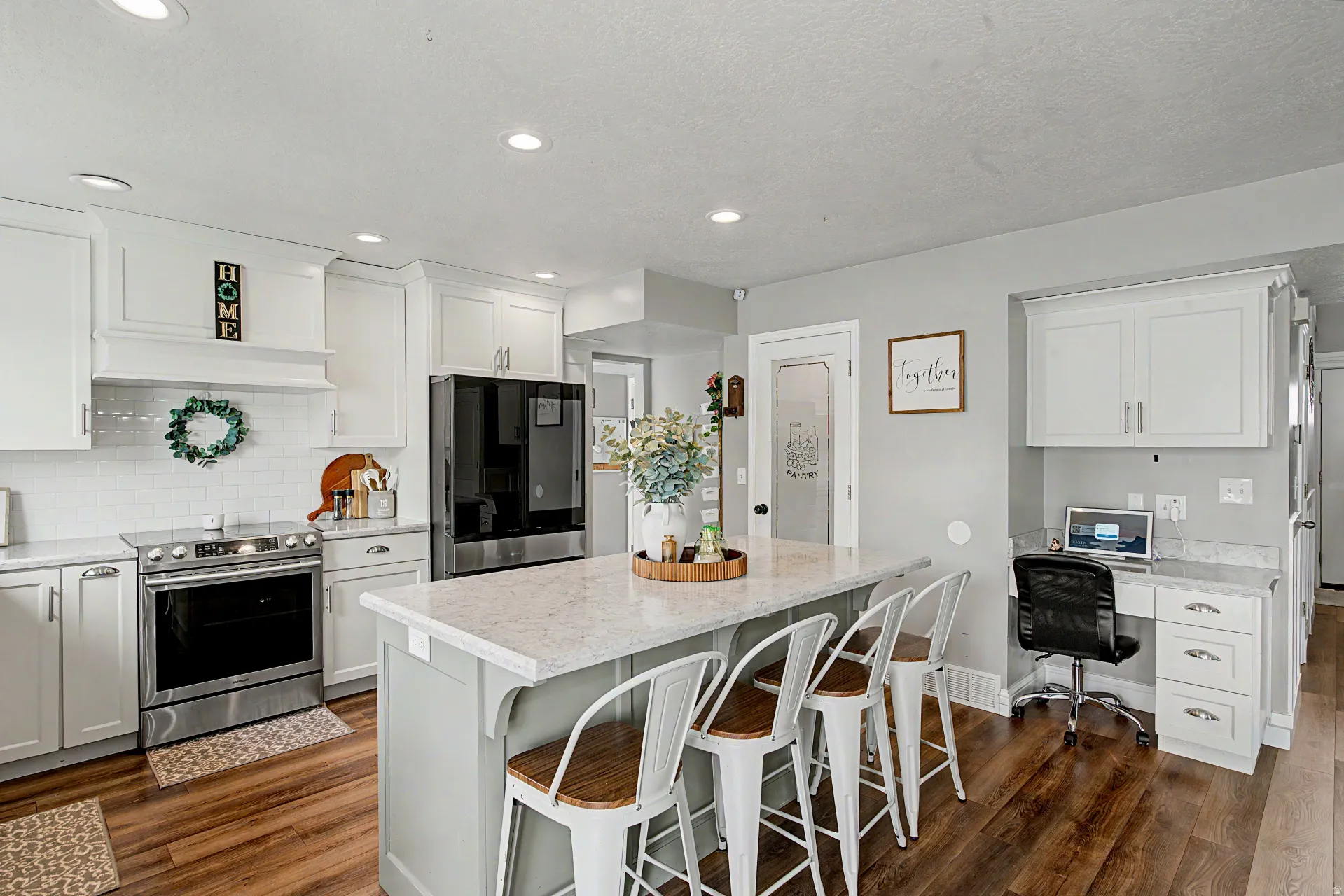 Kitchen with freestanding refrigerator, a center island, stainless steel electric stove, a kitchen breakfast bar, and light stone countertops