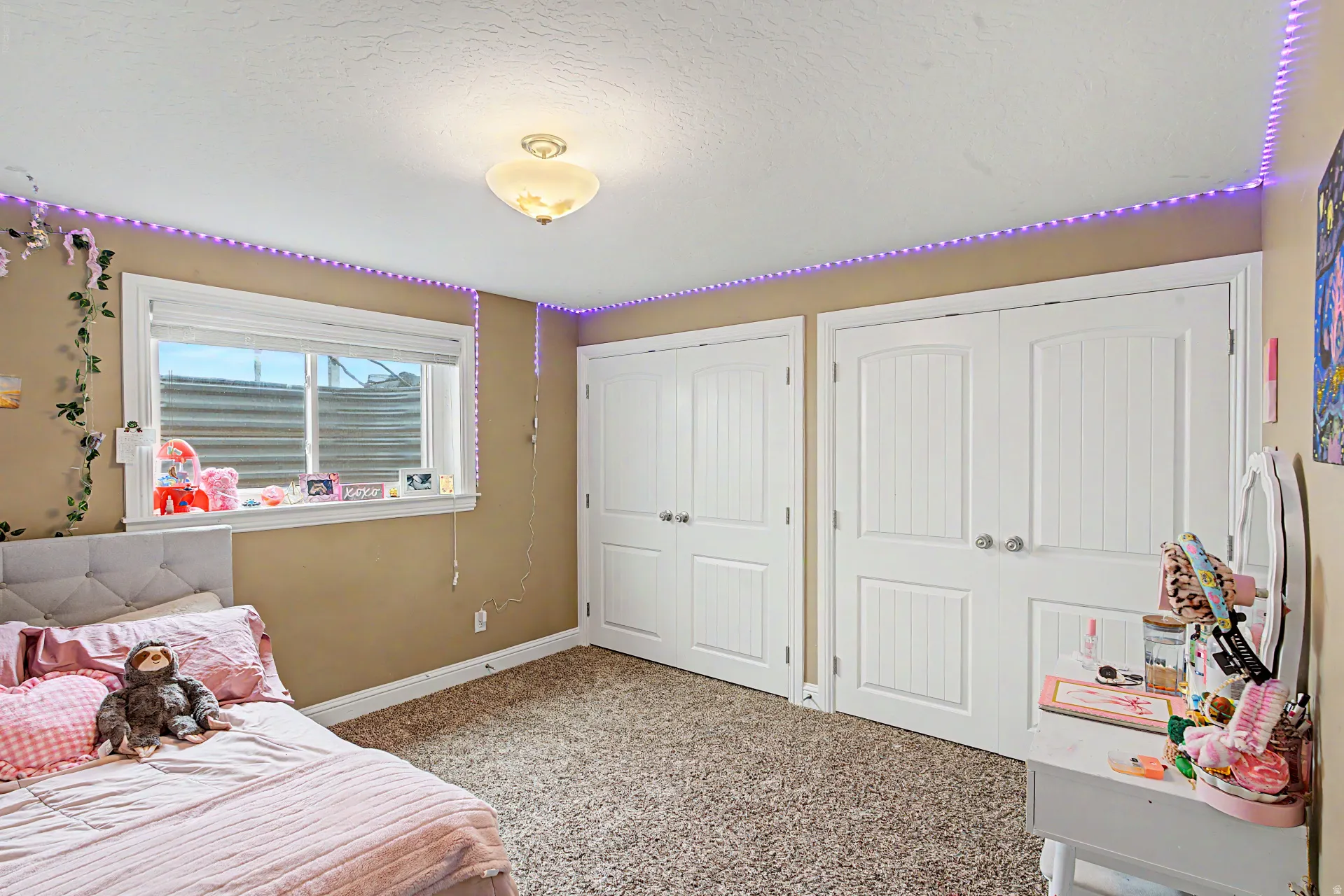 Bedroom featuring multiple closets, a textured ceiling, and light carpet