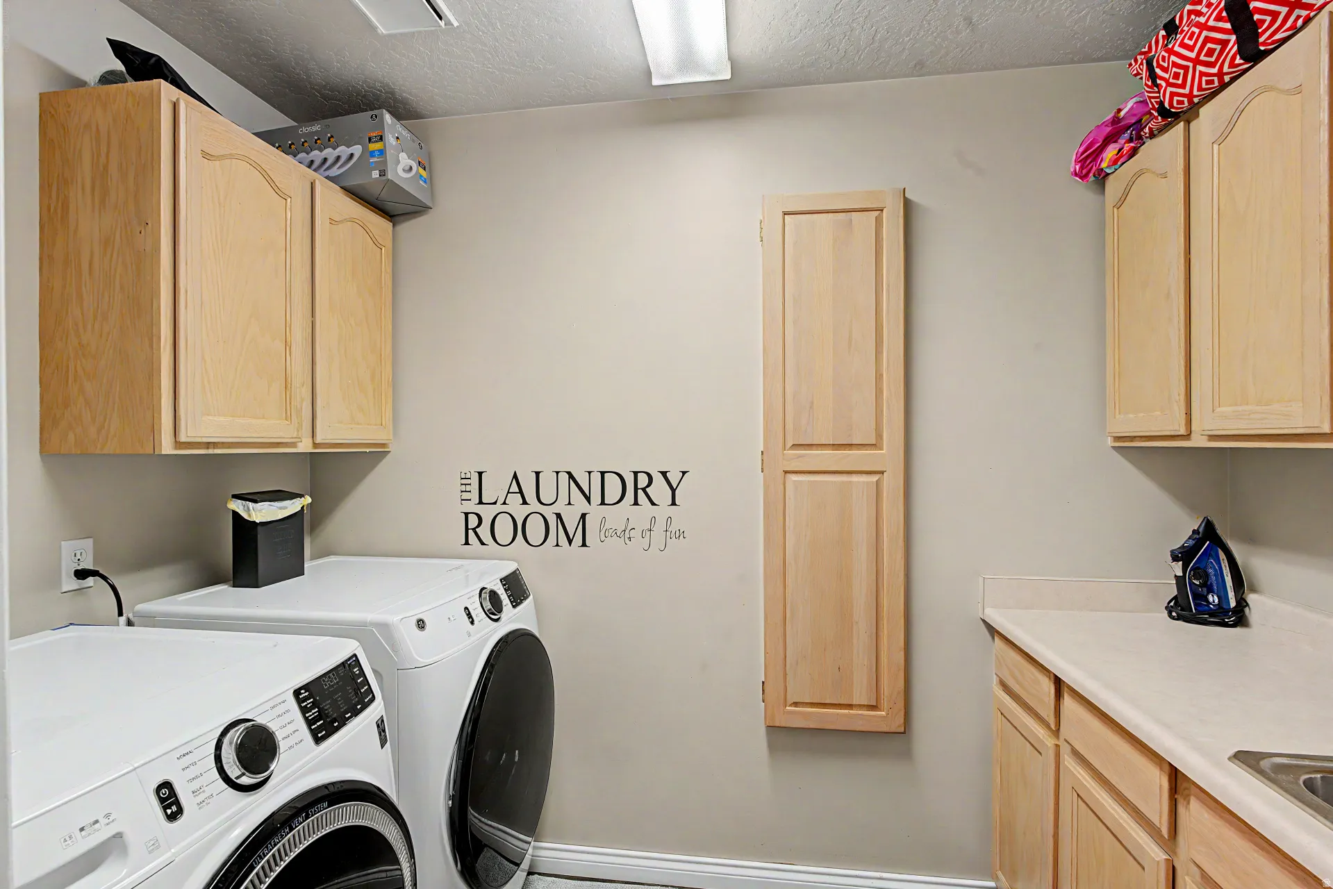 Laundry area featuring separate washer and dryer, a textured ceiling, and cabinet space