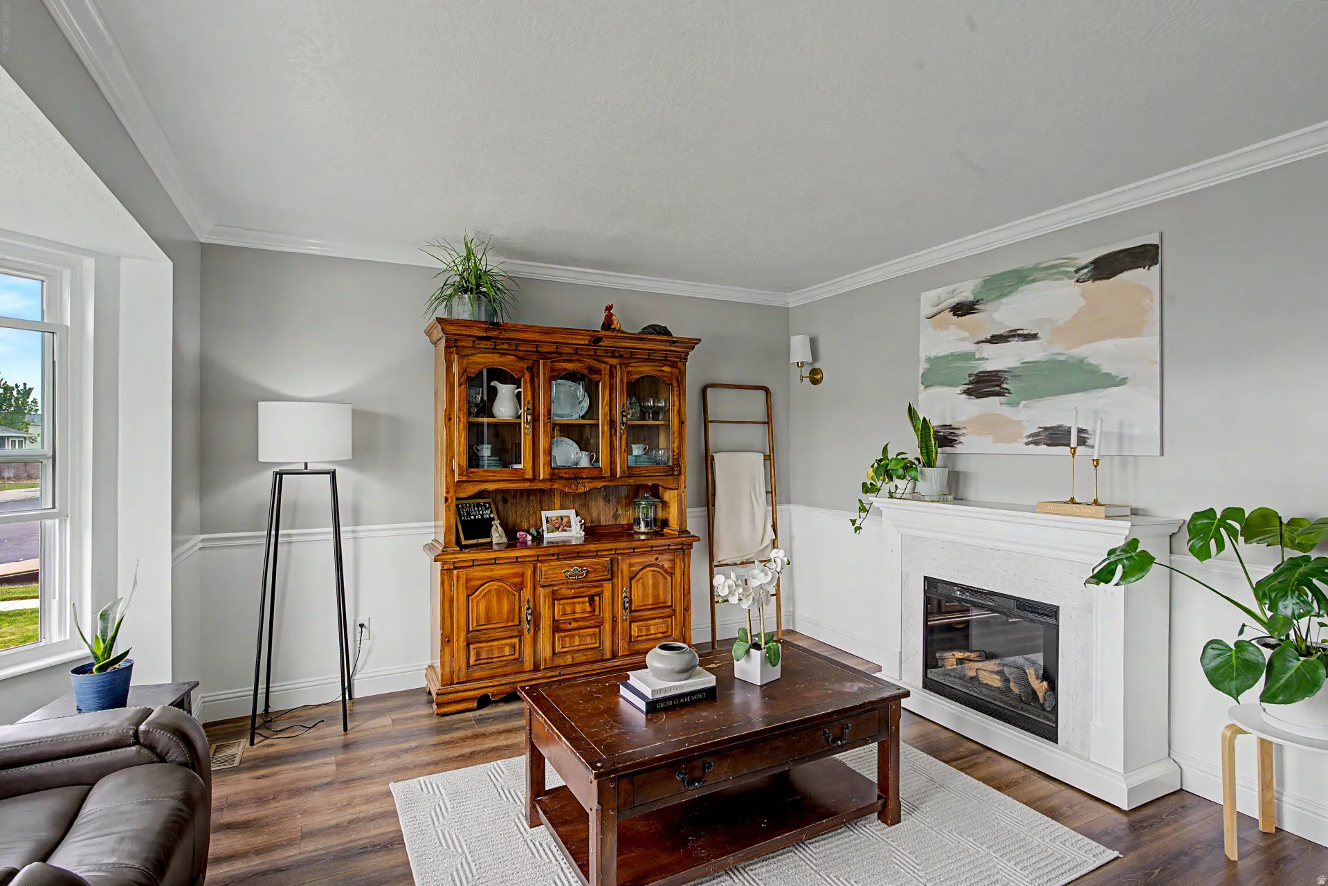 Living area with a glass covered fireplace, crown molding, dark wood finished floors, and plenty of natural light