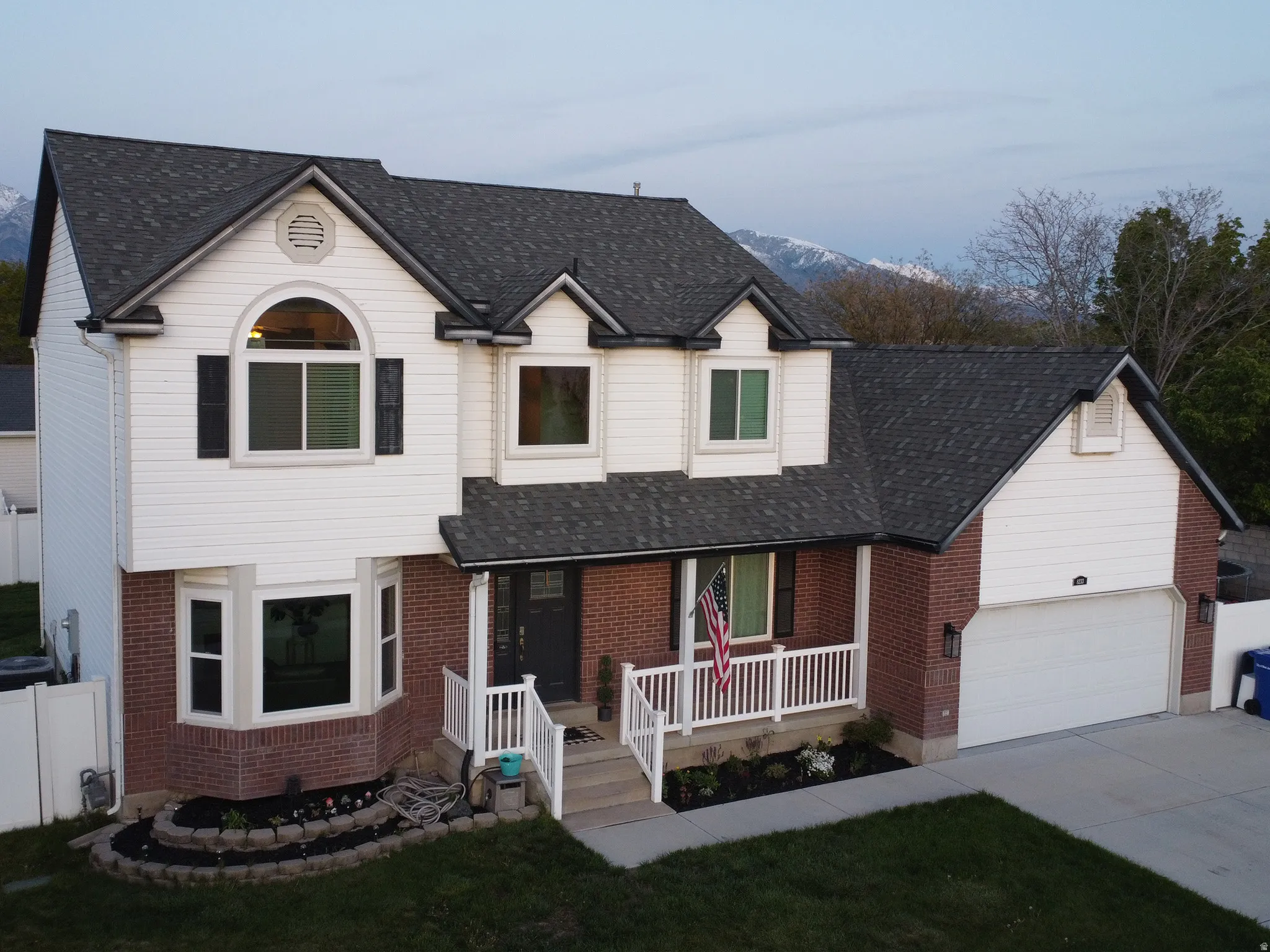Traditional-style house with covered porch, brick siding, concrete driveway, and a shingled roof