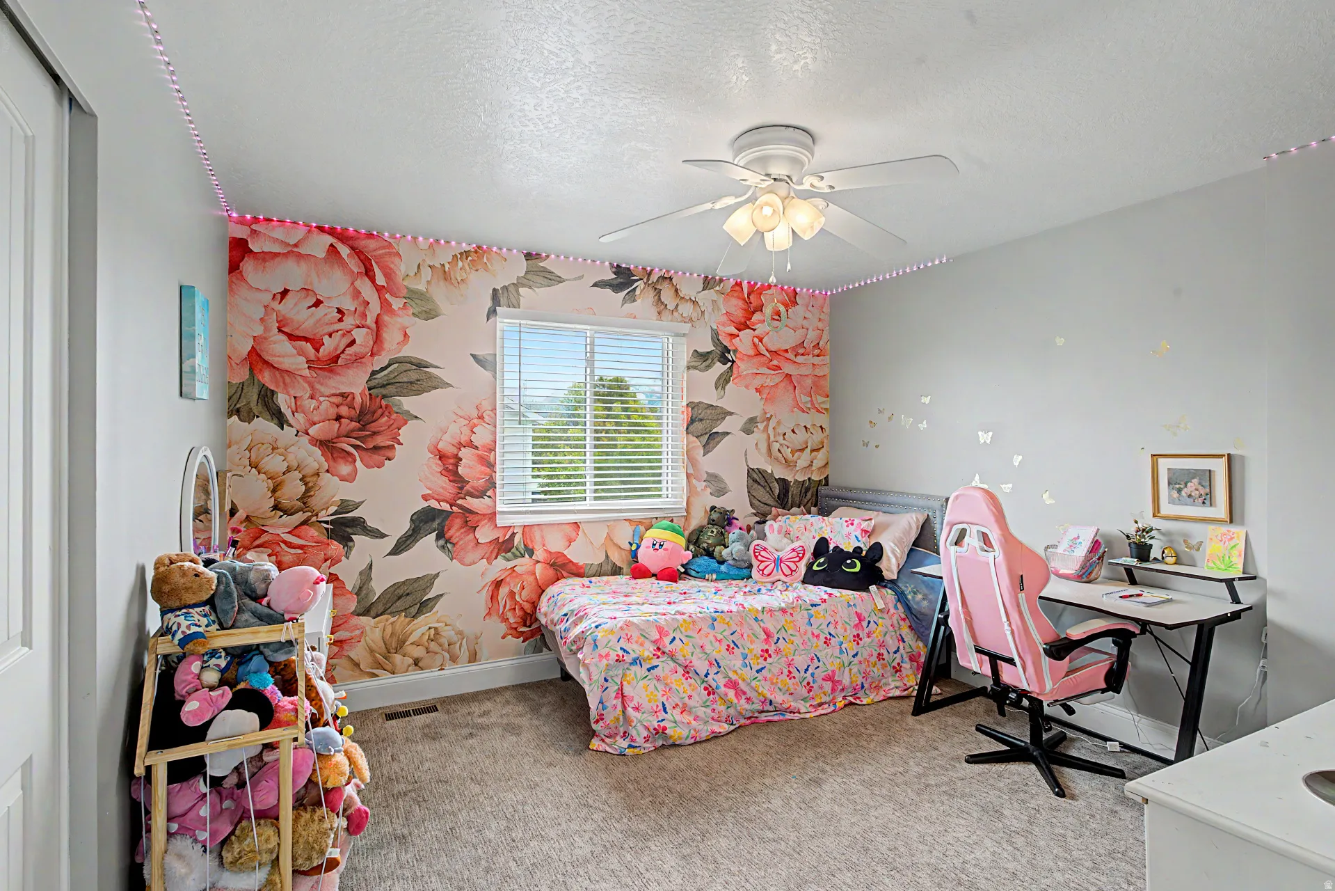 Bedroom featuring light colored carpet, a textured ceiling, ceiling fan, wallpapered walls, and an accent wall