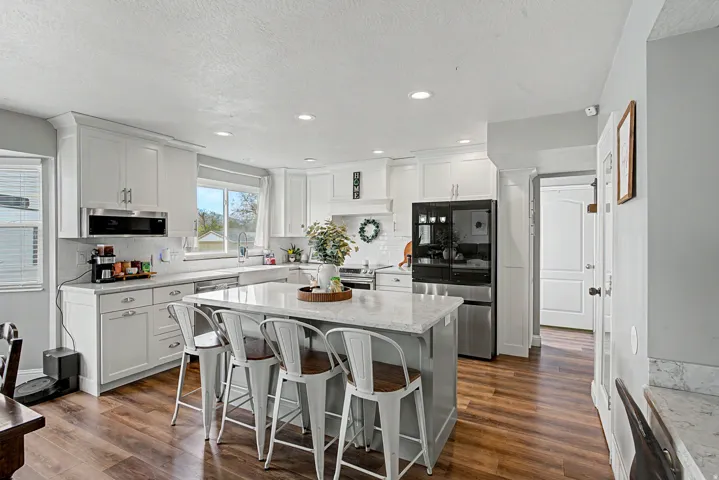 Kitchen featuring a breakfast bar, stainless steel appliances, tasteful backsplash, white cabinets, and recessed lighting