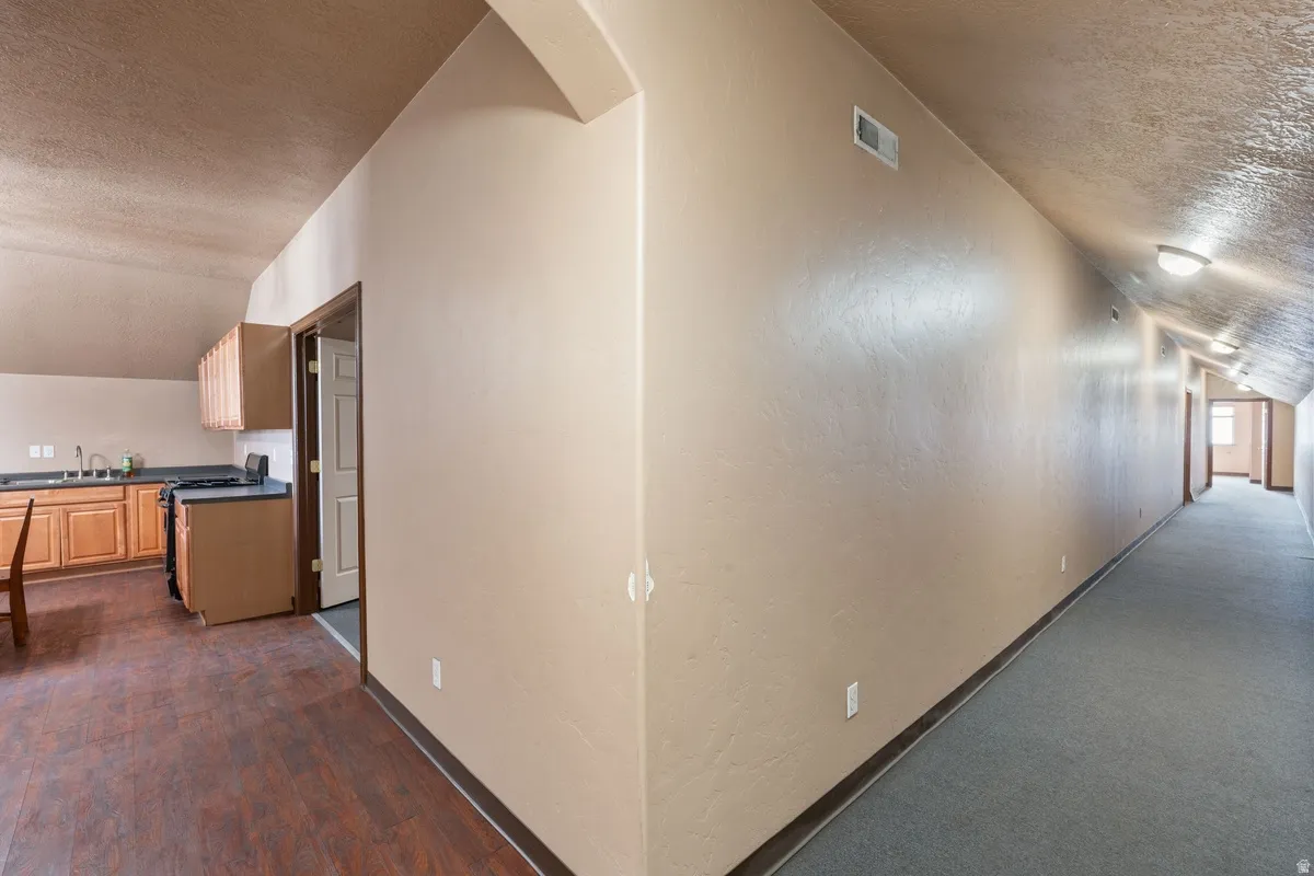 Corridor with a textured wall and dark wood-style flooring