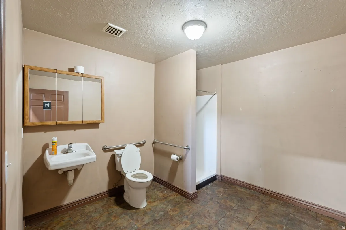Bathroom with a textured ceiling and toilet