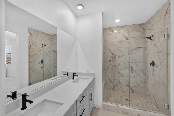 Walk-in shower with clear glass enclosure and marble-look tile surround