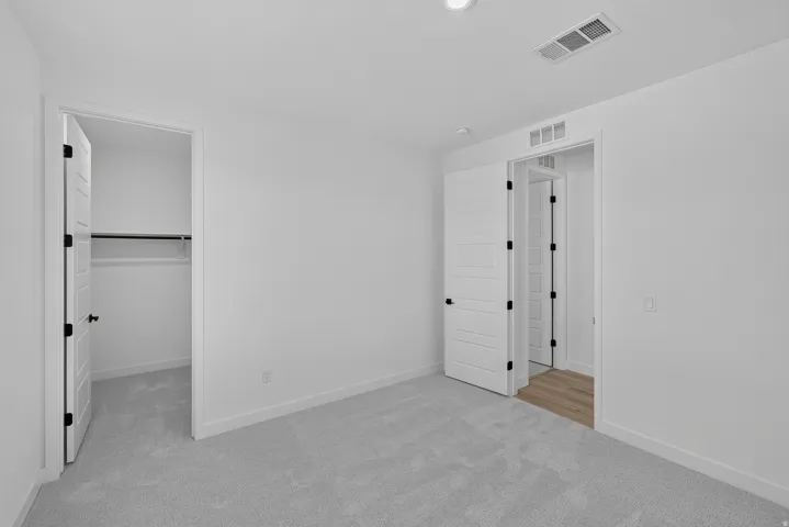Spacious bedroom featuring neutral wall finishes, recessed ceiling lighting, and dual closets with white panel doors and black hardware