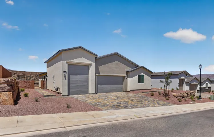 Contemporary stucco exterior featuring a two-car garage, an additional single-car garage, and a paver driveway