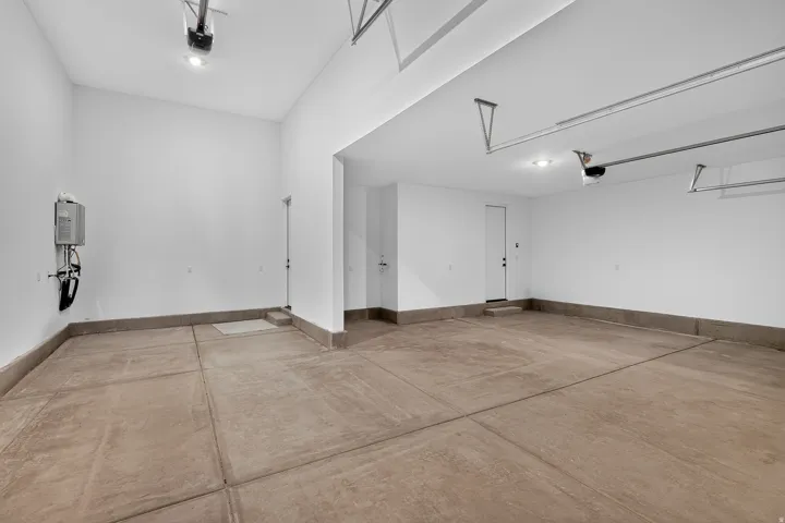 Two-car garage featuring concrete flooring, a tankless water heater, and overhead lighting